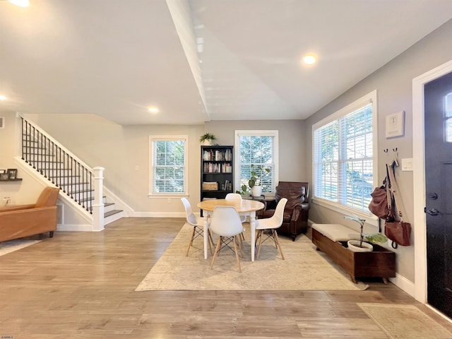 dining room with lofted ceiling, a healthy amount of sunlight, and light wood-type flooring