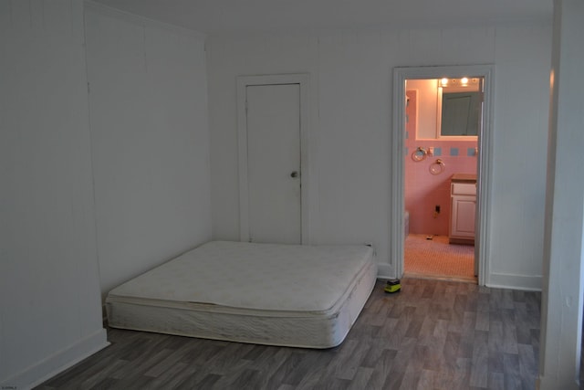 bedroom featuring dark wood-type flooring and ensuite bath