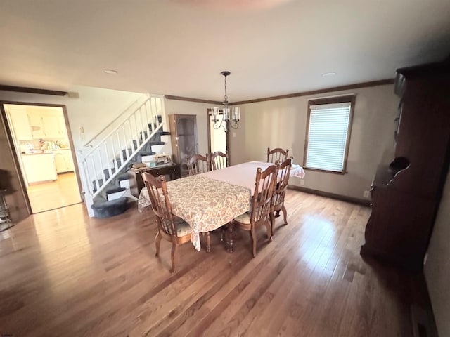 dining room featuring washer / clothes dryer, a notable chandelier, ornamental molding, and light hardwood / wood-style floors