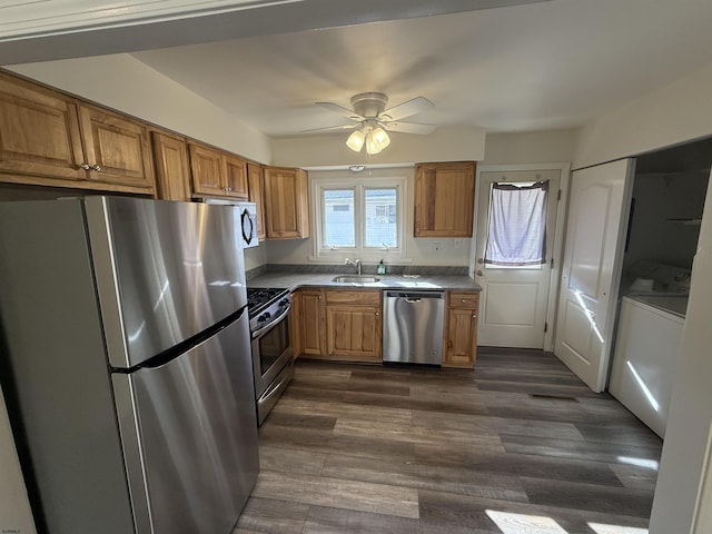 kitchen with stainless steel appliances, washer / dryer, dark wood-type flooring, and sink