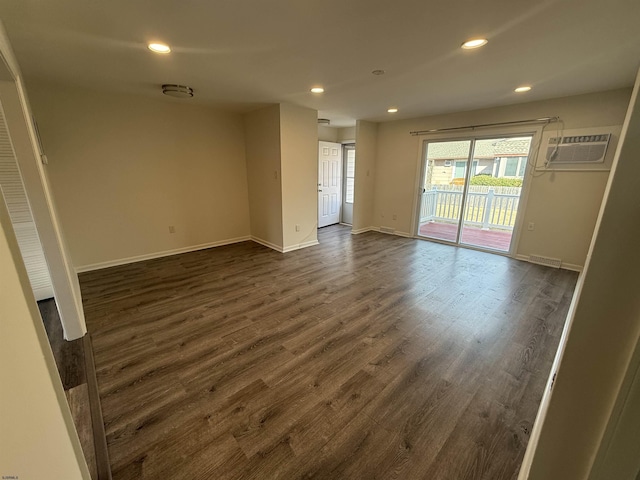 unfurnished room featuring dark hardwood / wood-style floors and an AC wall unit