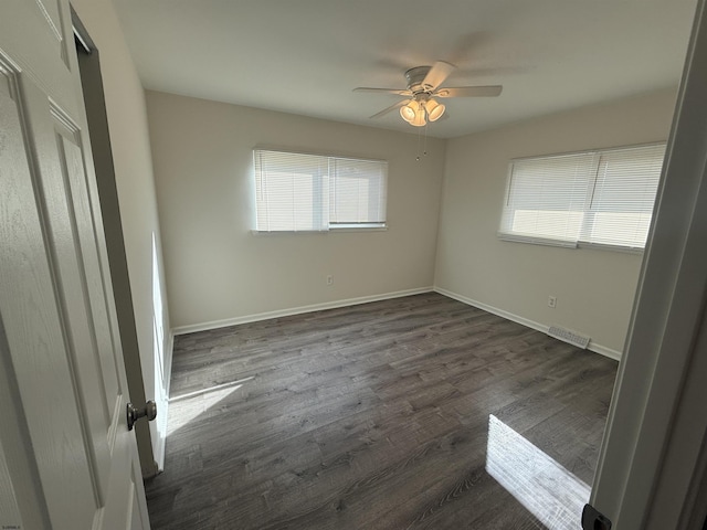 unfurnished bedroom featuring multiple windows, dark hardwood / wood-style flooring, and ceiling fan