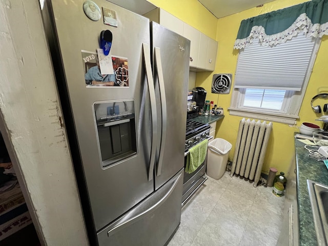 kitchen with appliances with stainless steel finishes, sink, radiator heating unit, and white cabinets