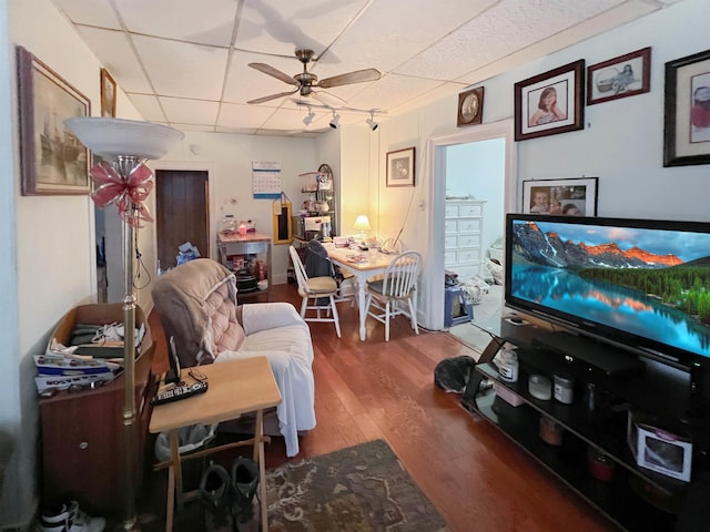 living room featuring a drop ceiling, hardwood / wood-style flooring, and ceiling fan