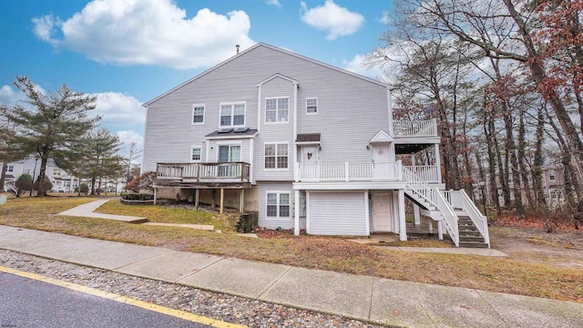 rear view of house featuring a wooden deck, a garage, and a yard