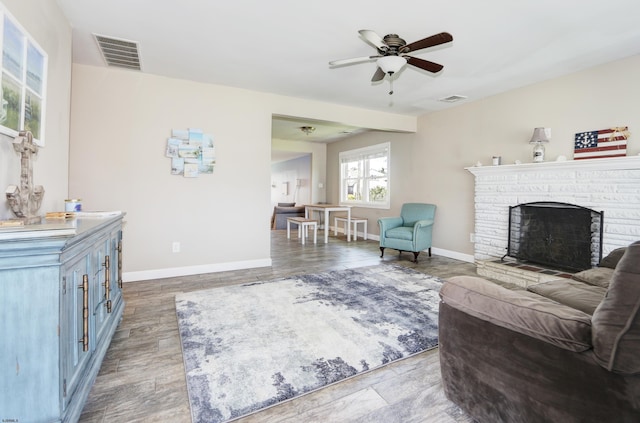 living room with ceiling fan, a brick fireplace, and light wood-type flooring