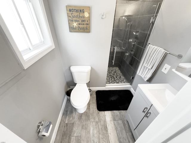 bathroom with hardwood / wood-style flooring, vanity, a shower with shower door, and toilet