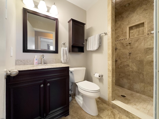 bathroom with vanity, a tile shower, and toilet