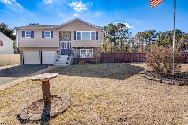 raised ranch featuring a garage and a front lawn