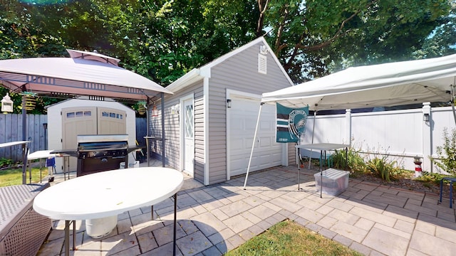 view of patio / terrace featuring a gazebo, a storage unit, a grill, and a garage