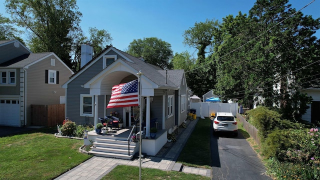 view of front of house with a garage, covered porch, and a front lawn