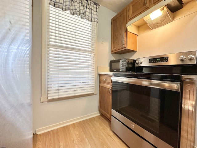 kitchen featuring extractor fan, stainless steel electric stove, and light wood-type flooring