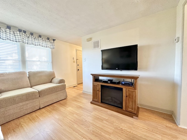 living room featuring light hardwood / wood-style flooring and a textured ceiling