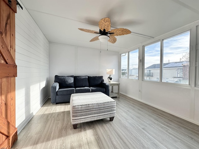 sunroom / solarium with a barn door and ceiling fan