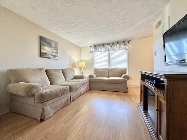 living room with a textured ceiling and light wood-type flooring