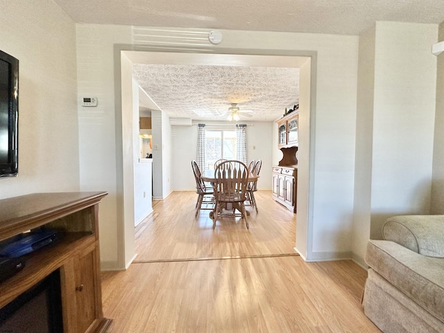 dining room with ceiling fan, light hardwood / wood-style flooring, and a textured ceiling