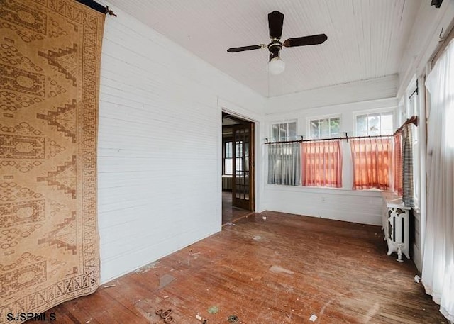 unfurnished sunroom featuring radiator and ceiling fan