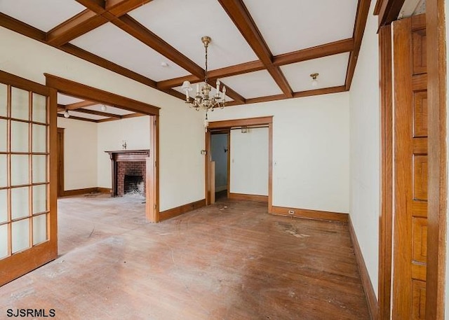 spare room with hardwood / wood-style flooring, coffered ceiling, a notable chandelier, a fireplace, and beamed ceiling