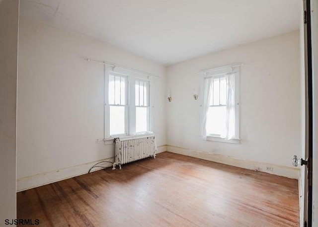 empty room with wood-type flooring and radiator