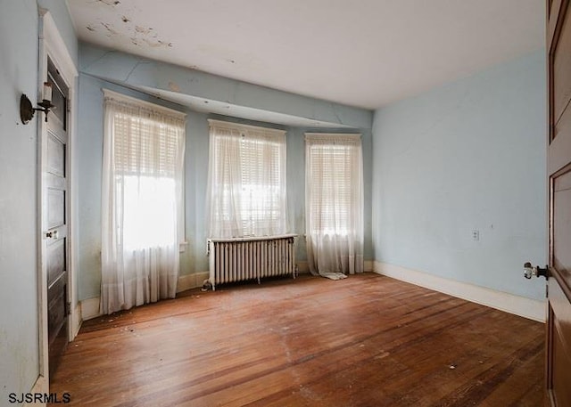 spare room featuring radiator heating unit and wood-type flooring