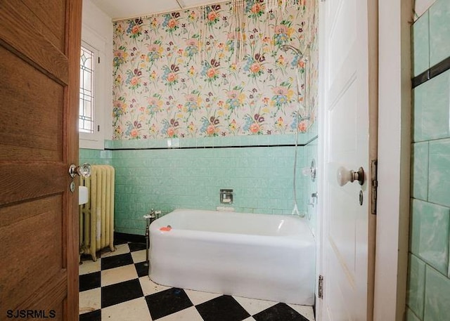 bathroom with tile walls, a bathtub, and radiator heating unit