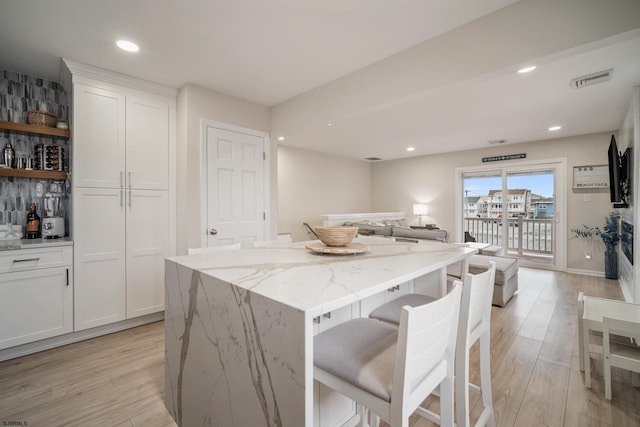 kitchen featuring white cabinetry, light stone countertops, and a kitchen island