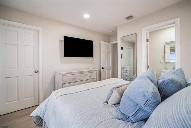 bedroom featuring ensuite bath and light wood-type flooring