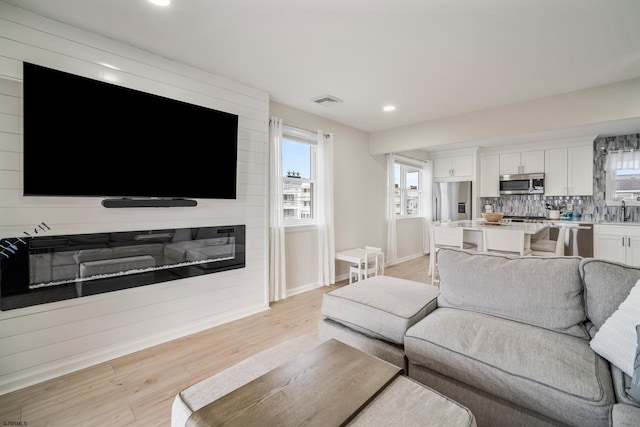 living room with sink, a fireplace, and light hardwood / wood-style floors