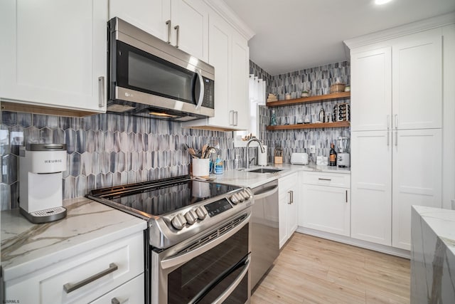 kitchen featuring sink, white cabinetry, light wood-type flooring, stainless steel appliances, and light stone countertops