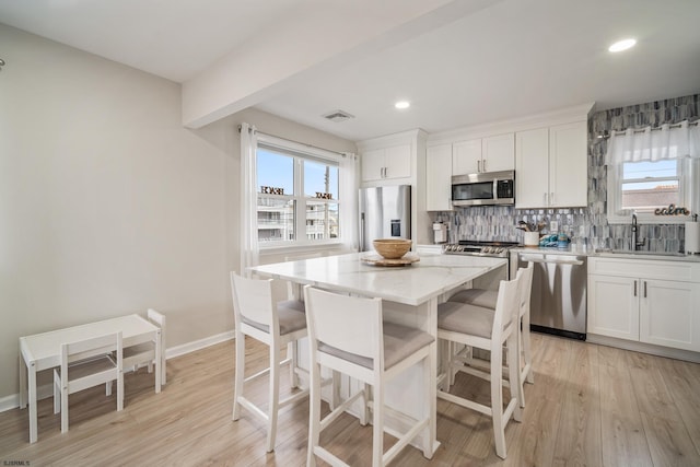 kitchen with stainless steel appliances, a center island, sink, and white cabinets