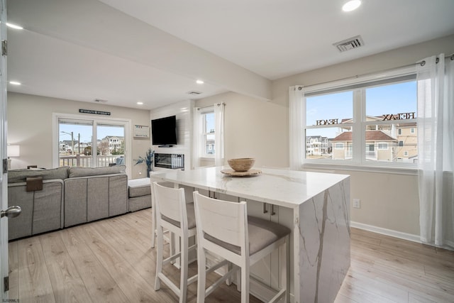 kitchen featuring a kitchen island, a breakfast bar area, light stone counters, and light hardwood / wood-style flooring