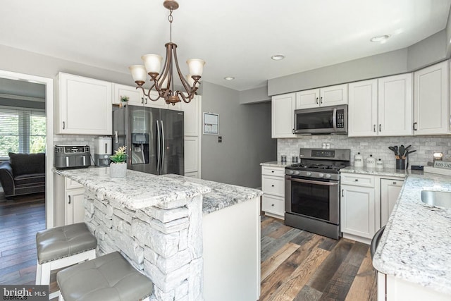 kitchen featuring hanging light fixtures, stainless steel appliances, and white cabinets