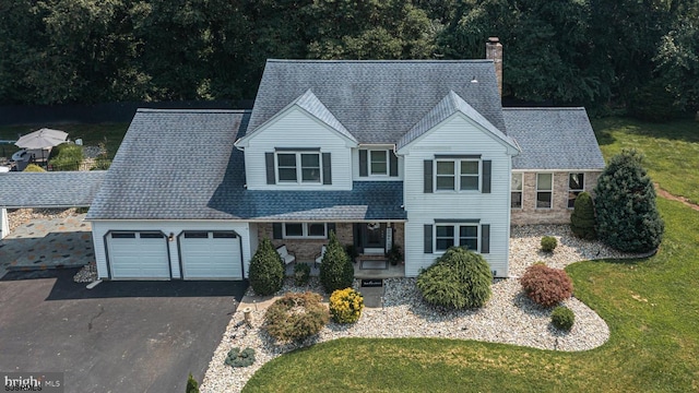 view of front of home featuring a garage, a front yard, and a porch