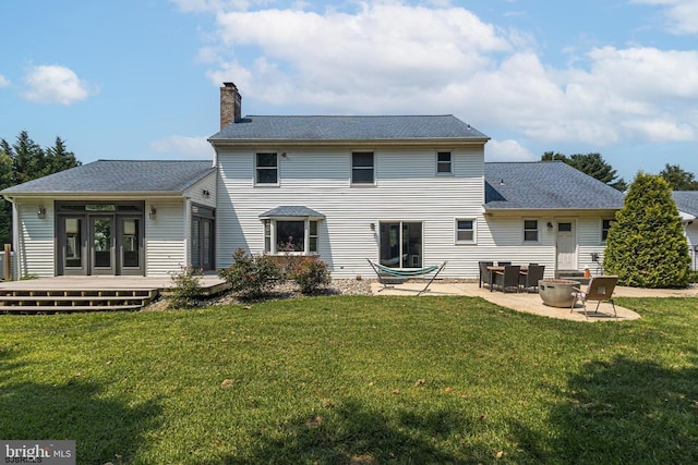 rear view of house with a patio area, a deck, french doors, and a lawn