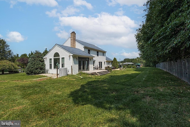 back of house with a deck and a lawn