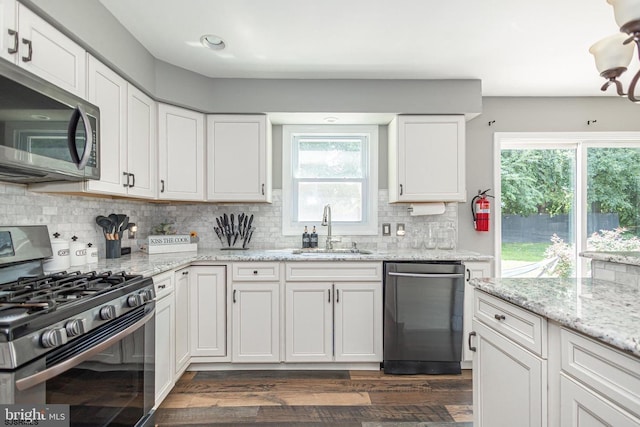 kitchen with sink, white cabinetry, tasteful backsplash, stainless steel appliances, and light stone countertops