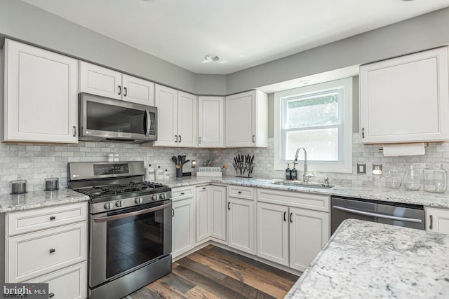 kitchen featuring appliances with stainless steel finishes, light stone countertops, sink, and white cabinets