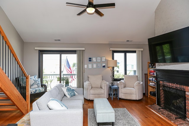 living room featuring a brick fireplace, a wealth of natural light, hardwood / wood-style floors, and ceiling fan