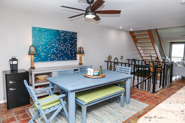 dining room with ceiling fan and dark tile patterned floors