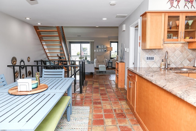 kitchen with sink, decorative backsplash, and light stone countertops