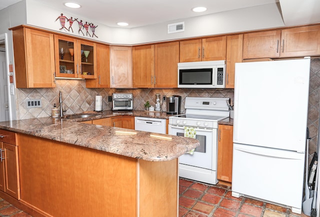 kitchen with sink, stone countertops, kitchen peninsula, white appliances, and decorative backsplash