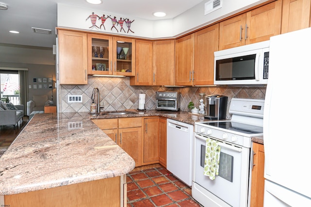 kitchen with sink, white appliances, backsplash, light stone counters, and kitchen peninsula