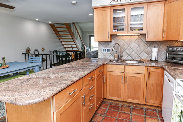 kitchen with sink, tasteful backsplash, dishwasher, kitchen peninsula, and light stone countertops