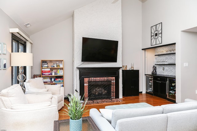 living room featuring indoor bar, a fireplace, vaulted ceiling, and hardwood / wood-style floors