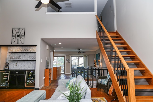 interior space featuring wood-type flooring, beverage cooler, ceiling fan, and indoor bar