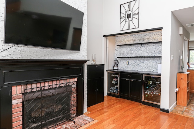 bar with wine cooler and light wood-type flooring