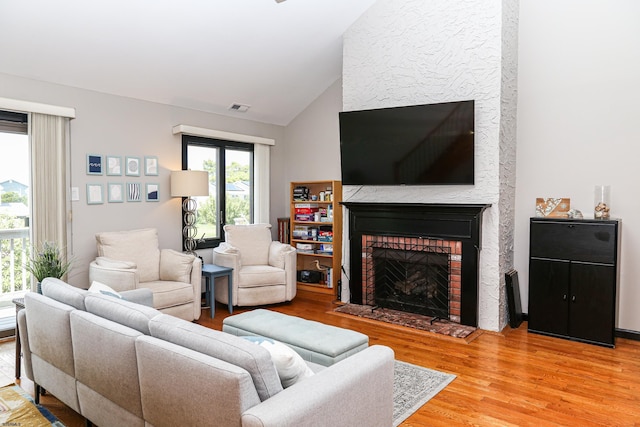 living room with hardwood / wood-style flooring, lofted ceiling, and a fireplace