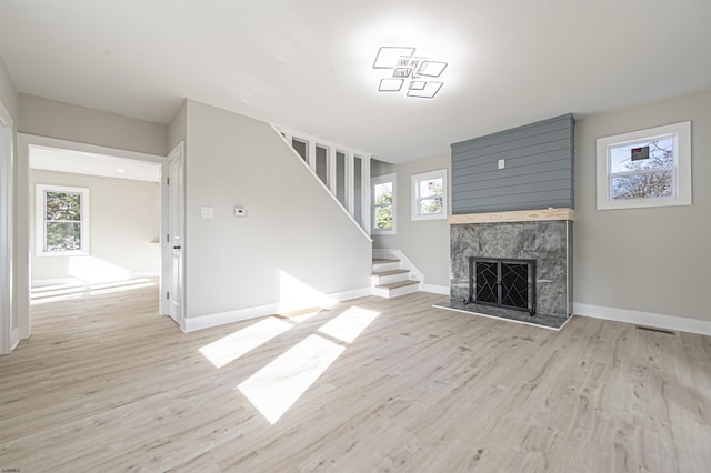 unfurnished living room with plenty of natural light, light wood-type flooring, and a high end fireplace