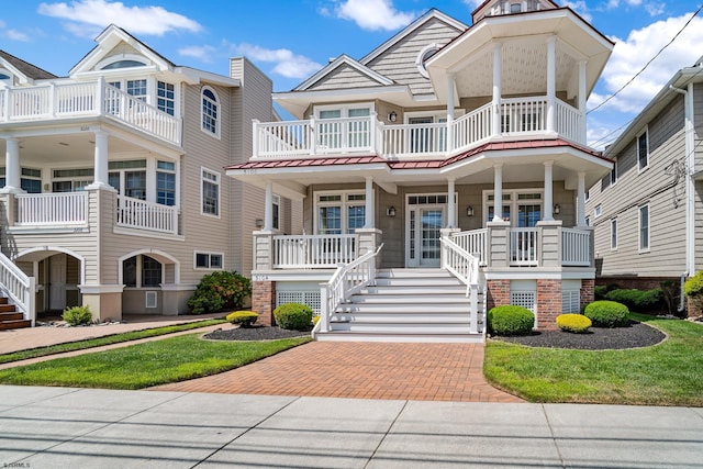 view of front of property featuring a front yard, a balcony, and a porch