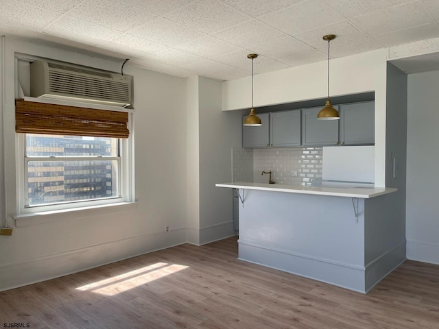 kitchen featuring tasteful backsplash, a kitchen breakfast bar, kitchen peninsula, and light hardwood / wood-style flooring